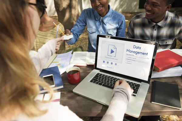 Studenti seduti a tavola con libri e laptop — Foto Stock