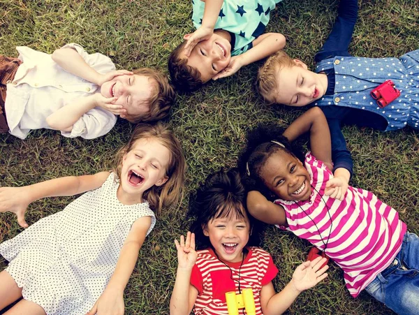 Niños tumbados en la hierba — Foto de Stock