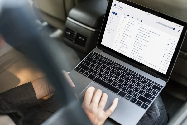 Бизнесмен, использующий ноутбук в машине — стоковое фото