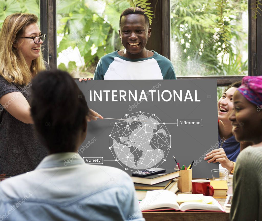 Group of multi-ethnic students learning together, blonde woman holds pointer showing on placard with International Concept