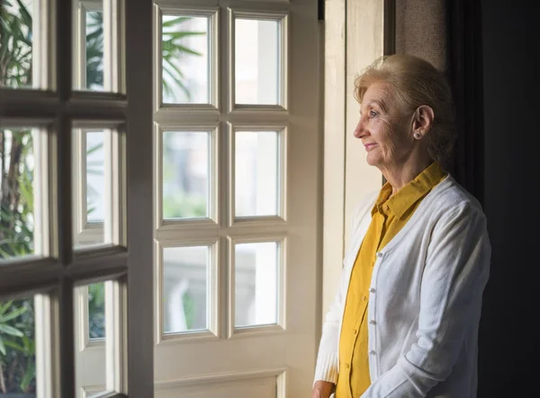 Senior woman standing near open door — стоковое фото