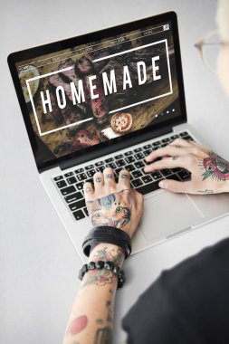 Dövmeli kişi dizüstü bilgisayarda yazarak.