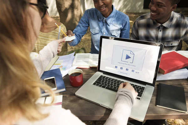 Studenti seduti a tavola con libri e laptop — Foto Stock