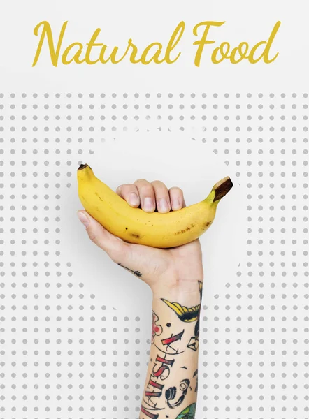 Tattooed person holding banana. — Stock Photo, Image