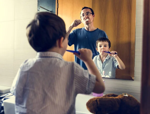 Padre enseñando a hijo a cepillarse los dientes — Foto de Stock