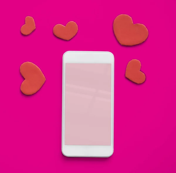 Мобильный телефон и красные сердца — стоковое фото