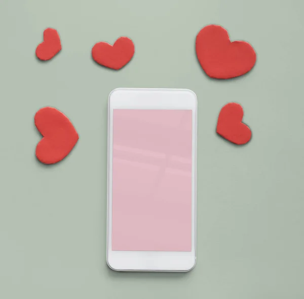Мобильный телефон и красные сердца — стоковое фото
