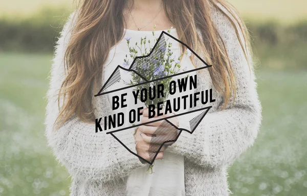 Woman standing in field and holding flowers — Stock Photo, Image