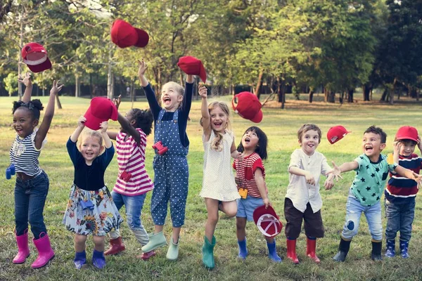Students throwing red caps in the air — Stock Photo, Image