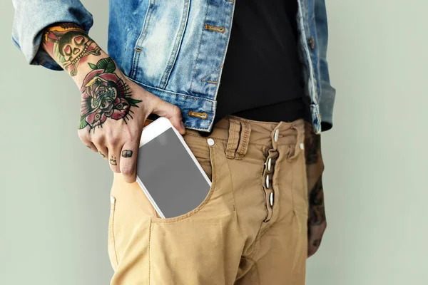 Tätowierte Hand steckt Handy in Tasche — Stockfoto