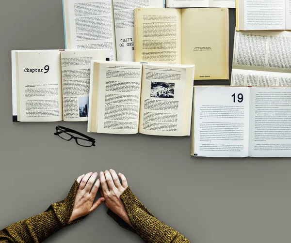Руки за столом со многими книгами — стоковое фото