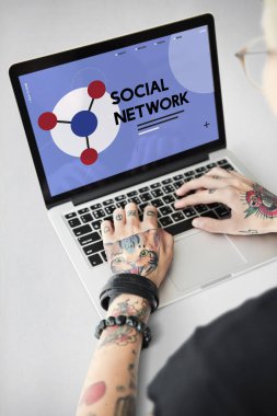 Dövmeli kişi dizüstü bilgisayarda yazarak.