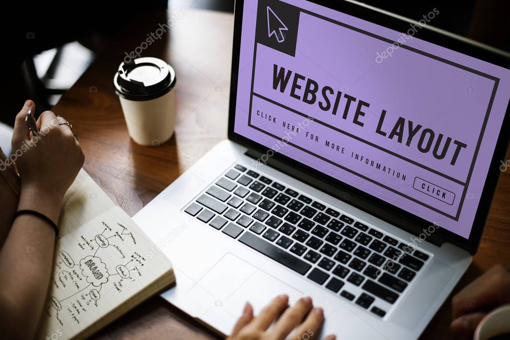 Woman typing on laptop keyboard, coffee cup on table, notebook concept text on monitor screen: Website Layout