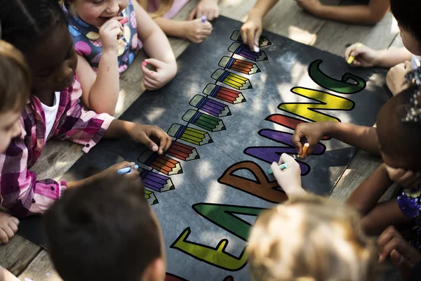 Children drawing with chalks on the black board