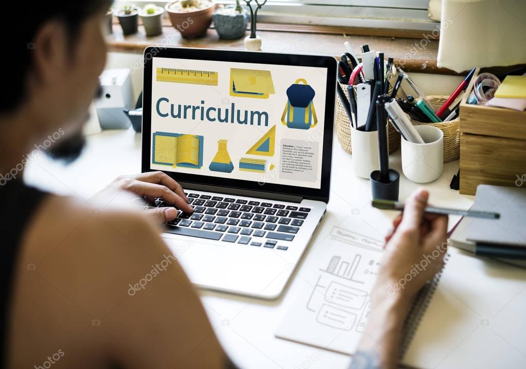 Tattooed man working at laptop, screen with Curriculum