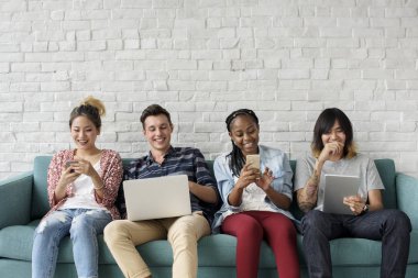 dizüstü bilgisayar ile kanepede oturan öğrenciler