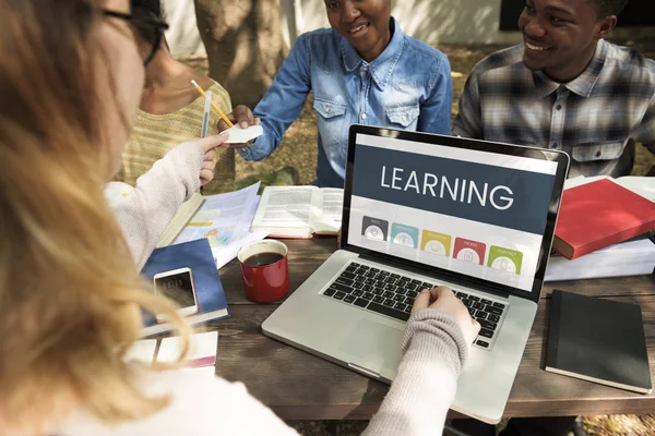 Studenten zittend aan tafel met boeken en laptop — Stockfoto