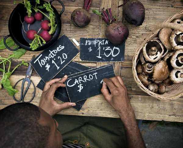 Продавець чоловік пише ціну за овочі — стокове фото