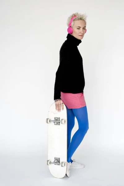Donna in cuffia con skateboard — Foto Stock