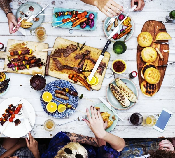Amici seduti a tavola con vari cibi — Foto Stock
