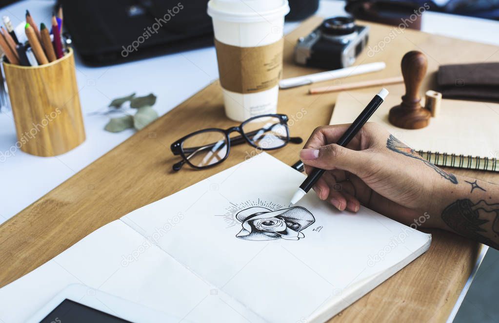 male hand drawing artwork on notebook