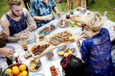 Çeşitli gıda ile masada oturan arkadaşlar
