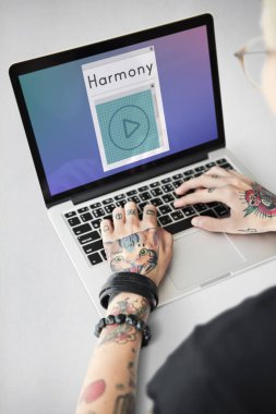 Dövmeli kişi dizüstü bilgisayarda yazarak.