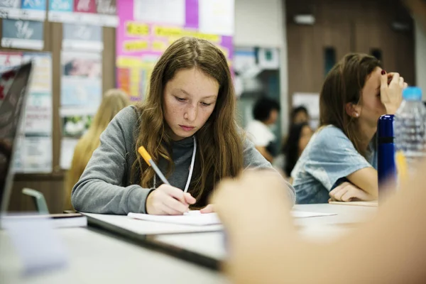 Girl writing notes in classroom — Stock Photo, Image
