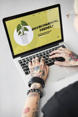 Dövmeli kişi dizüstü bilgisayarda yazarak.