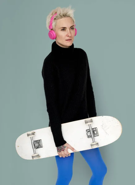 Жінка в навушниках зі скейтбордом — стокове фото