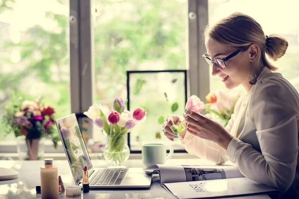 Mujer escribiendo en el ordenador portátil y olfateando flor —  Fotos de Stock