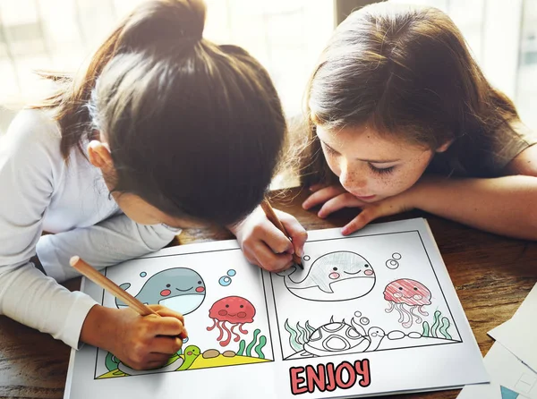 Twee meisjes tekening in het boek kleurplaten — Stockfoto