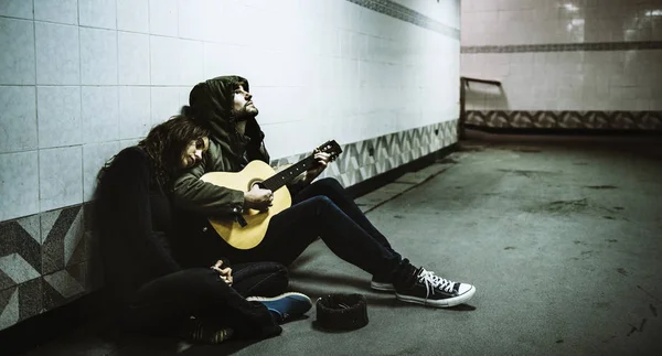 homeless couple playing guitar for money