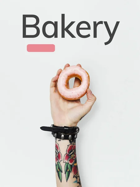 Frau hält rosa Donut in der Hand — Stockfoto