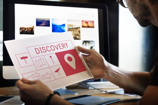 Man holding picture in front of monitor screen — Stock Photo, Image