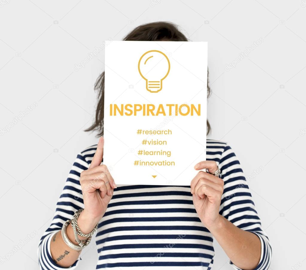Woman holding placard covering face, placard with Inspiration