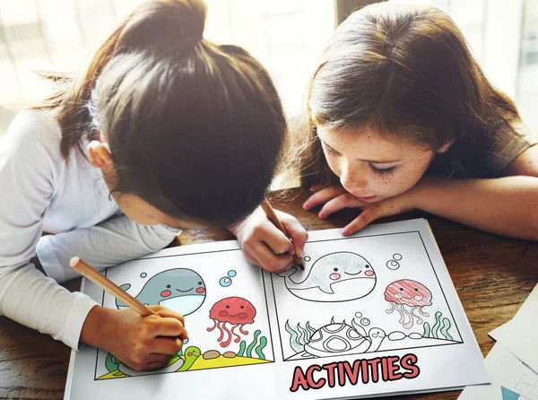 Two girls drawing in coloring book — Stock Photo, Image
