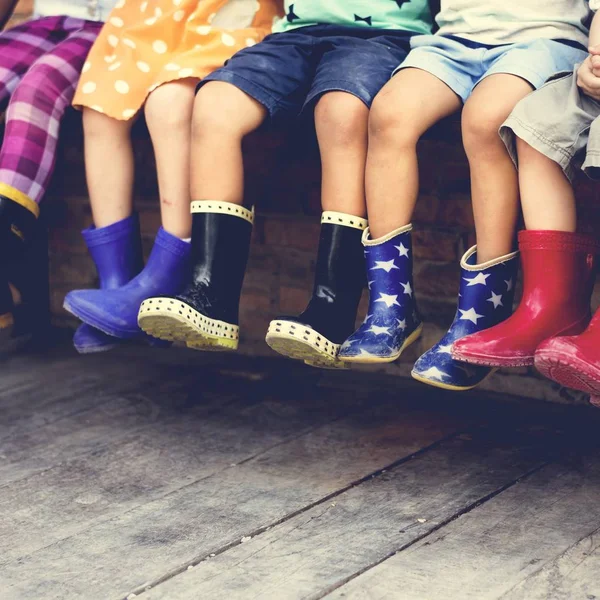 Niños se sientan juntos botas de goma — Foto de Stock