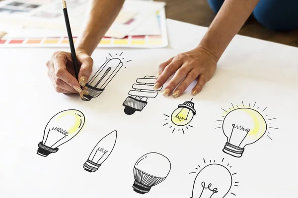 Person drawing light bulbs — Stock Photo, Image