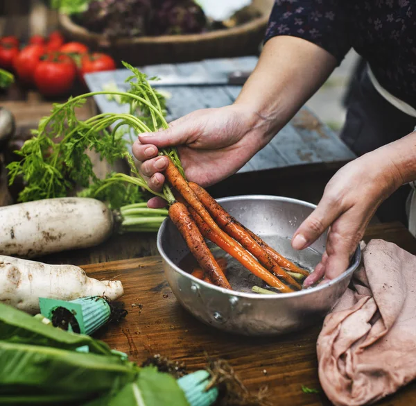 Женские руки чистят морковь в миске — стоковое фото
