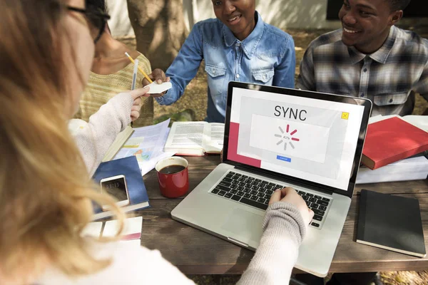 Studenten zittend aan tafel met boeken en laptop — Stockfoto