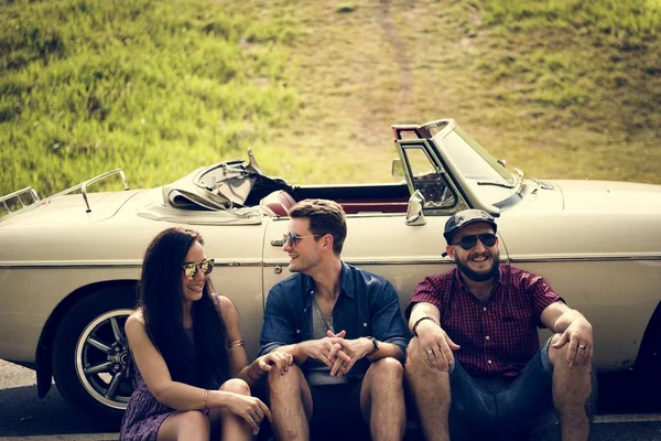 Yolda arabanın yanında oturan arkadaşlar