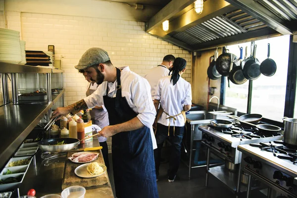 Zespół kucharzy pracujących w kuchni — Zdjęcie stockowe