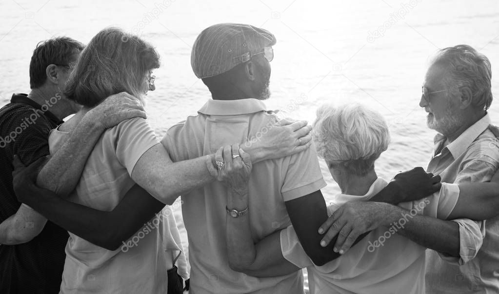 senior people embracing near sea