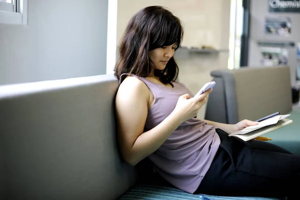 妇女坐和使用智能手机 — 图库照片