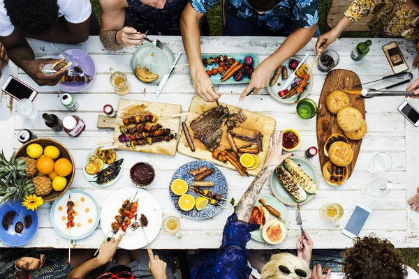 Друзья сидят за столом с разнообразной едой — стоковое фото
