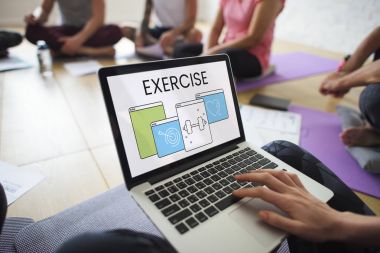 yoga sınıfında dizüstü bilgisayar kullanan kişi