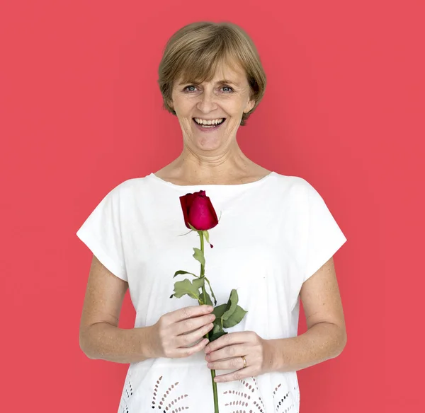 Senior vrouw bedrijf rode roos — Stockfoto