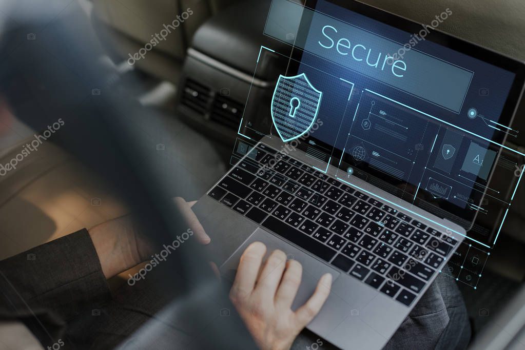 Partial view of hands, businessperson using laptop in car, graphic title: Secure