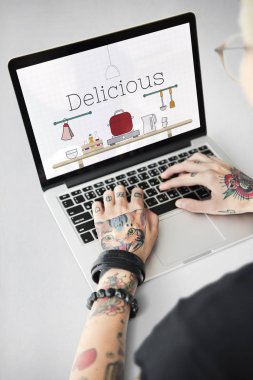 Dizüstü bilgisayarda yazarak dövmeli kadın eller